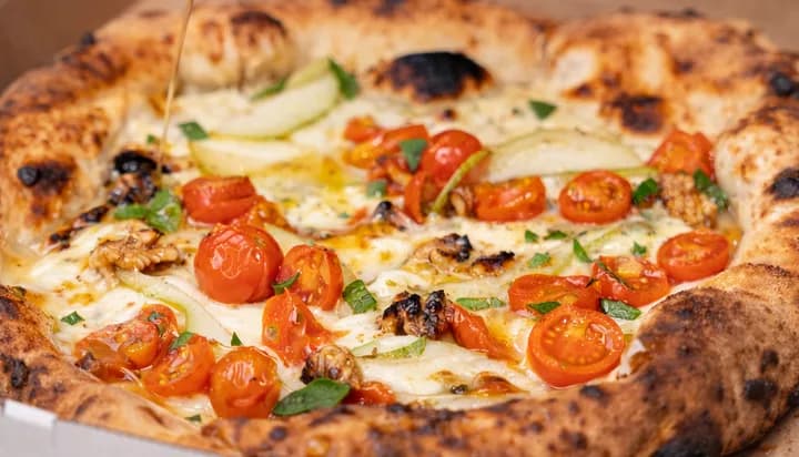 A wood-fired pizza topped with cherry tomatoes