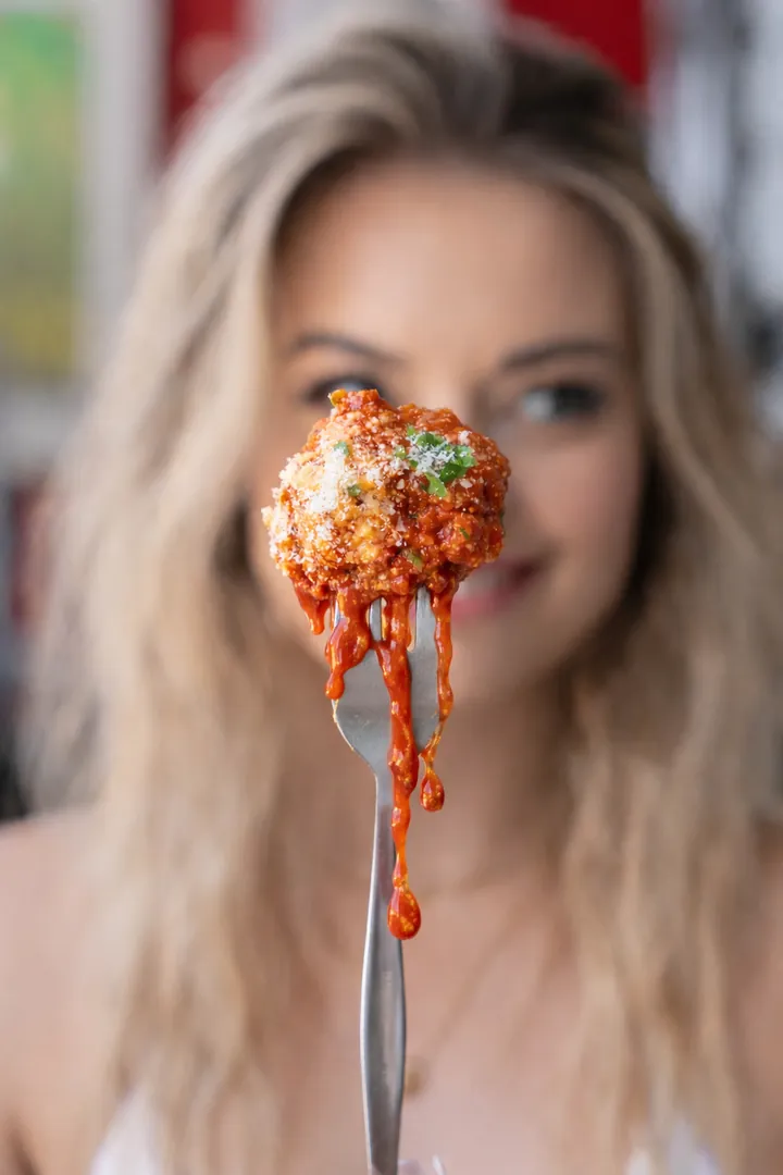 A meatball in sauce held up on a fork