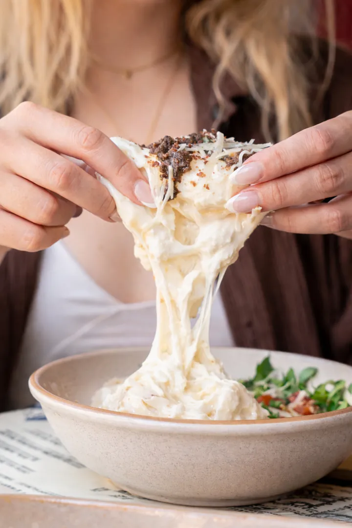 Cheese pulled from a bowl of pasta