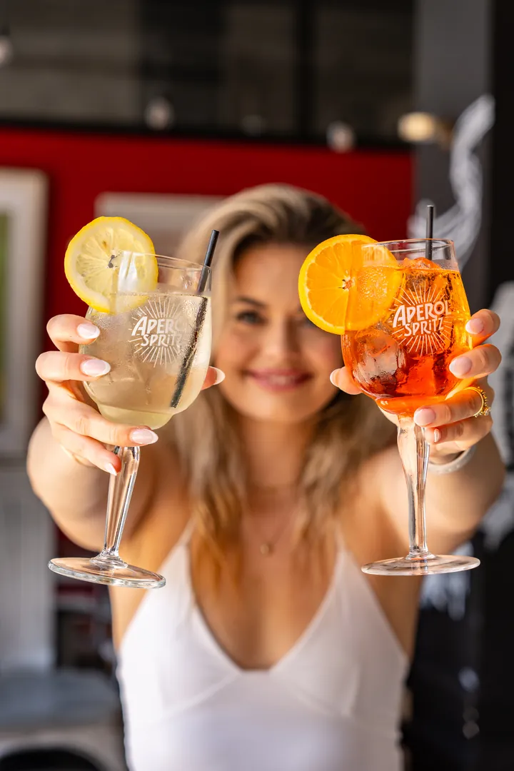 Two Aperol spritzes held up to the camera