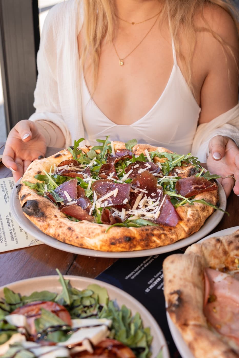 A woman holding a pizza at a restaurant table